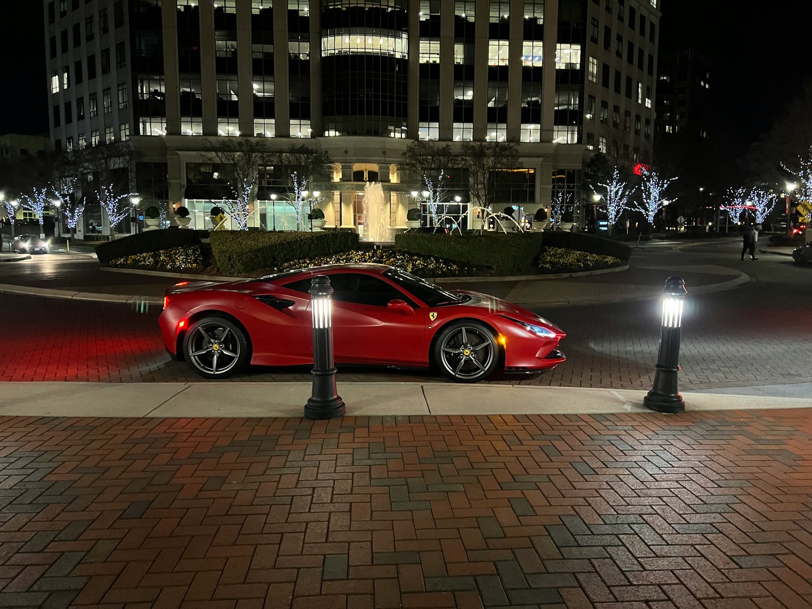 Ferrari F8 Tributo in Rosso Corsa parked at night, reflecting city lights across the ceramic-coated flanks.
